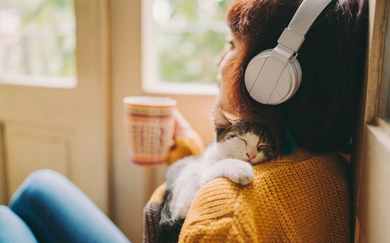 Woman at home listening to music and drinking coffee