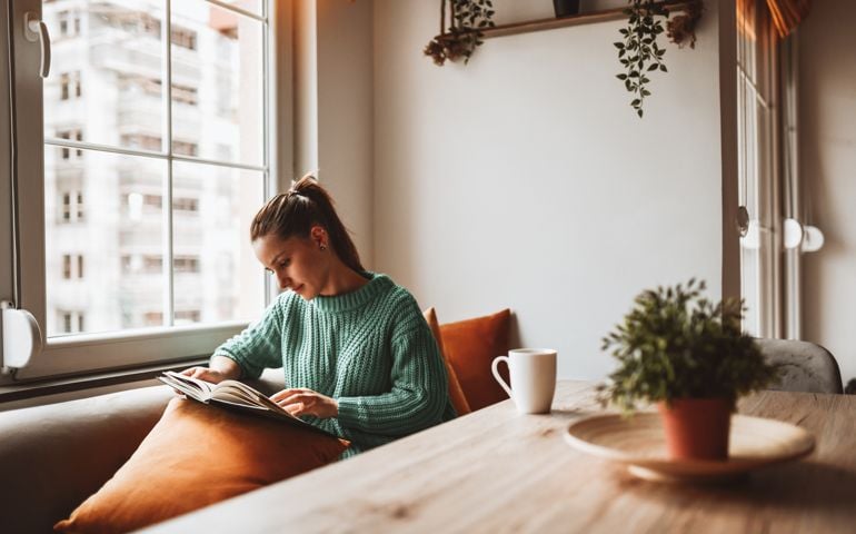Female Looking At Old Photo Album In Home Kitchen