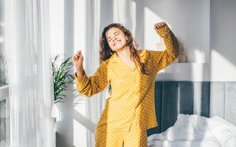 Woman in yellow pyjamas dancing in morning at home.