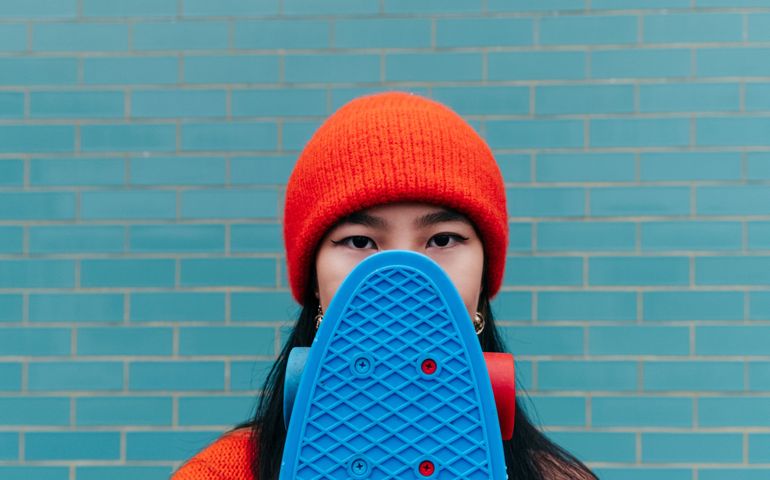 Woman Hiding Her Face With A Blue Skateboard