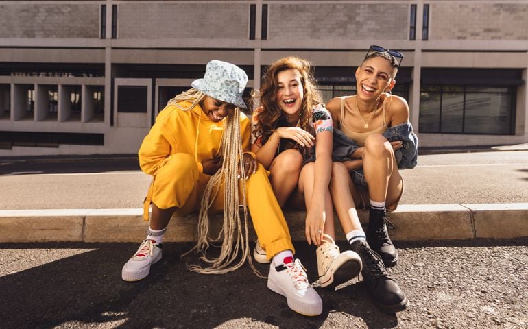 Group of female friends laughing cheerfully in the city. Generation z friends having fun while hanging out together outdoors.