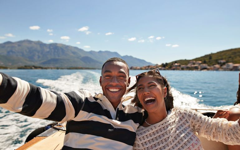 Happy young couple taking selfie while enjoying boat ride on sunny day