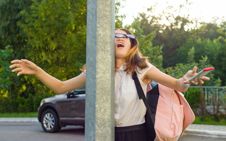 Portrait of young inattentive girl, distracted by mobile phone. Girl crashed into street post, dropped phone
