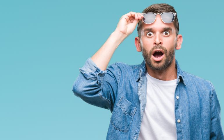 Young handsome man wearing sunglasses over isolated background afraid and shocked with surprise expression, fear and excited face.