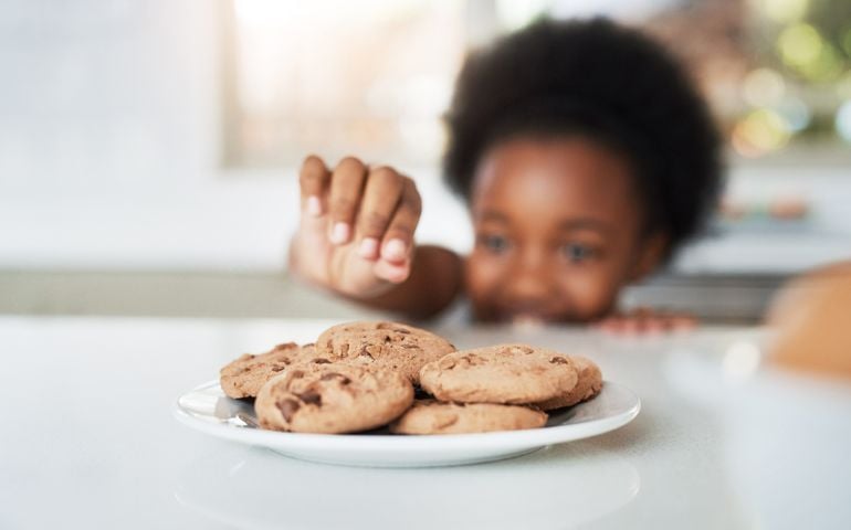 Cropped shot of an adorable little girl stealing cookies at home