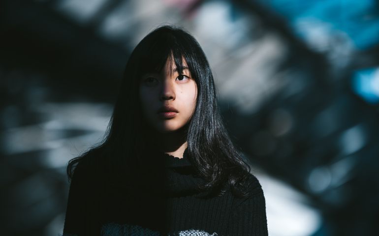 A portrait of a young woman while half of her face is lit by the sun and the other half is in the shadow.