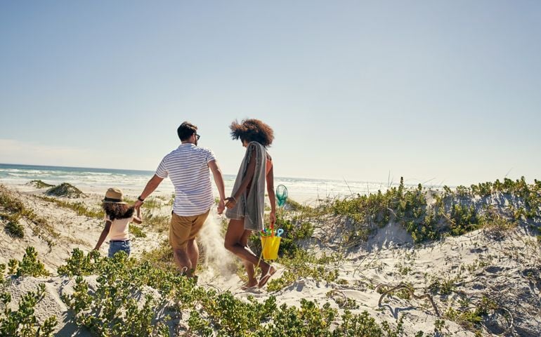 Rearview shot of a little girl and her parents spending time together at the beach