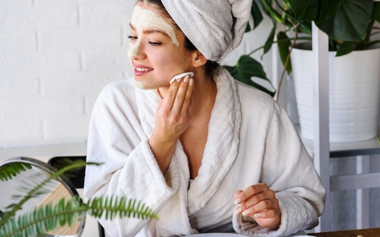 Young woman applying face mask at home.