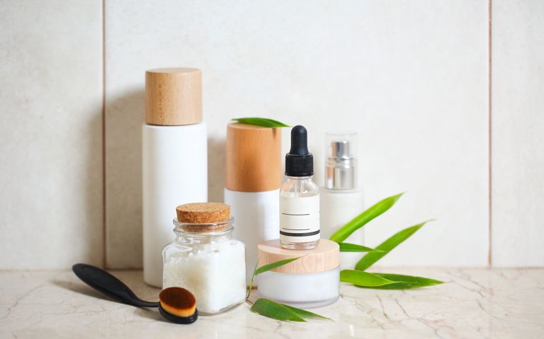 Face cream, serum, lotion, moisturizer and sea salt among bamboo leaves in the bath