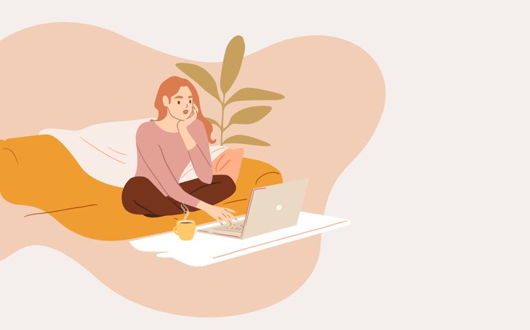 Young woman using computer while sitting on sofa at home