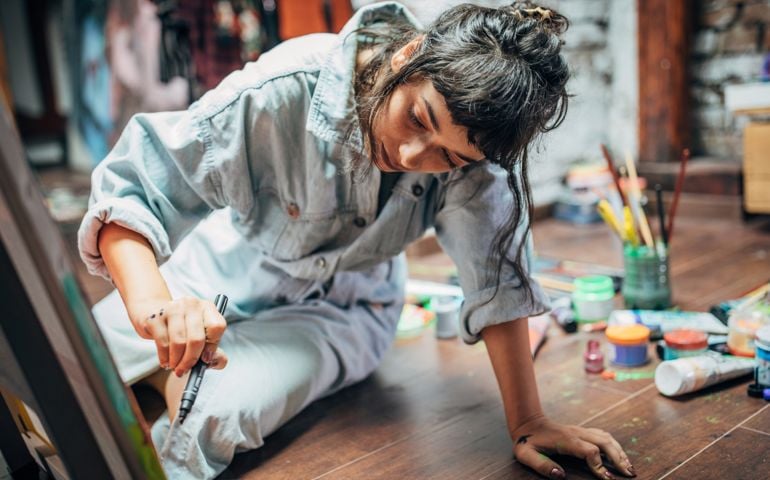One woman, beautiful lady artist, painting on the floor in studio.