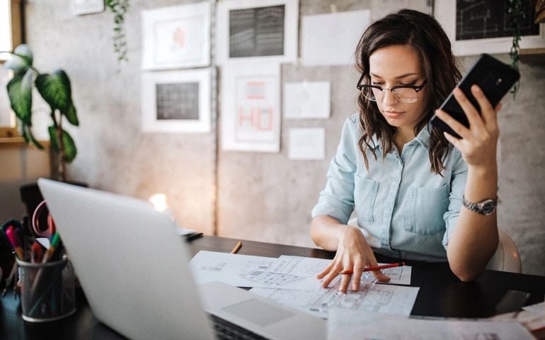 Young female entrepreneur using smart phone at modern working place