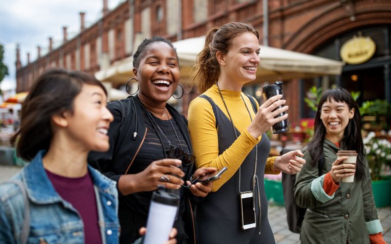 female friends with drinks walking in city