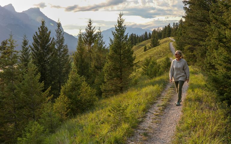 Mature woman walks down trail in the morning