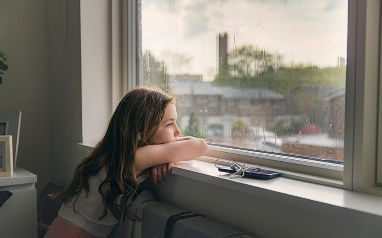 Young girl looking out of window on a rainy day
