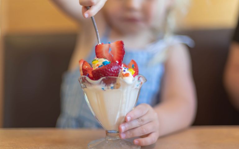 Midsection Of Girl Holding Ice Cream On Table