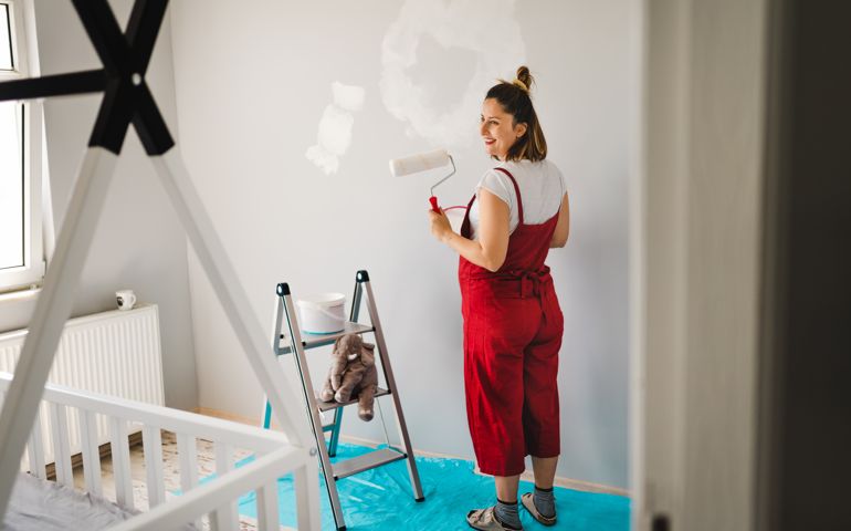Young Pregnant woman painting nursery