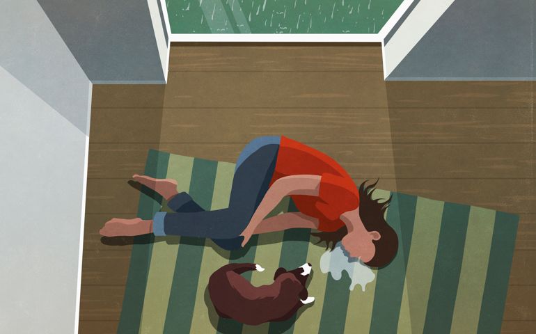 Dog laying next to depressed woman crying on floor