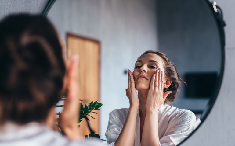 Woman applies foam to her face, cleansing her skin.