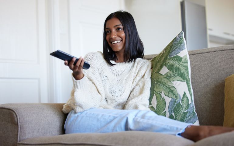 Shot of a beautiful young woman holding a remote control while sitting on the couch at home