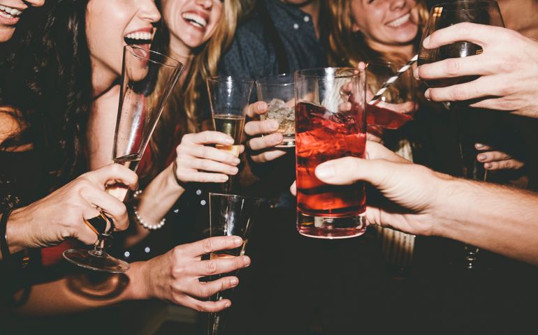 Cheerful male and female friends raising toast while partying together