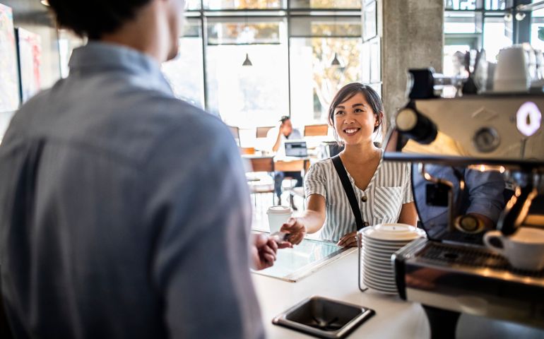 Young woman paying for coffee with credit card