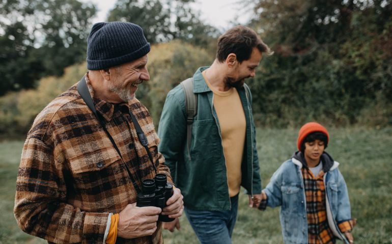 Three generations males hiking in woodland, exploring nature together.