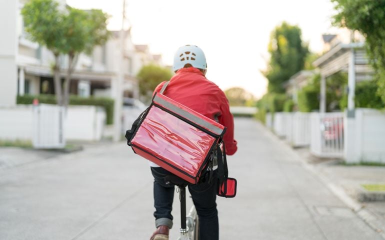 Male delivery guy on bicycle with backpack in the city.