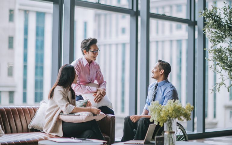white collar worker in wheelchair discussion in office lounge with his colleague