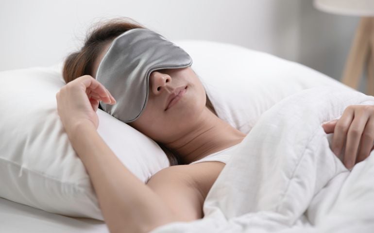 Young woman with eye mask sleeping in her bed and relaxing in the morning