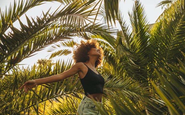 Pretty young woman among palm trees