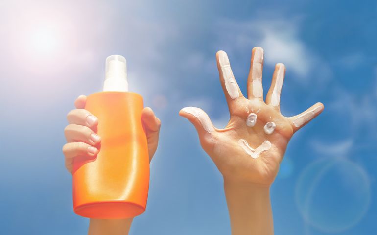 Two hands on blue sky, clouds and beams of sun background.