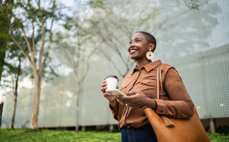 Business woman holding smartphone and looking away outdoors