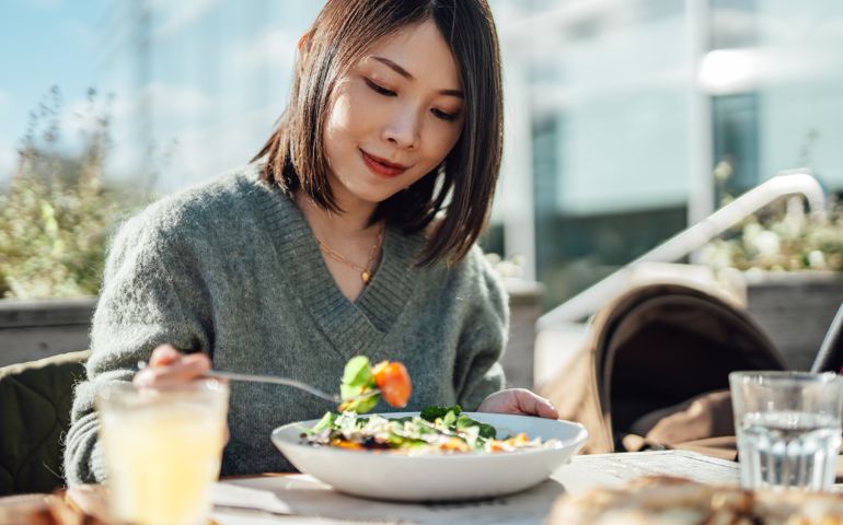 Young woman enjoying a vegan lunch at outdoor restaurant