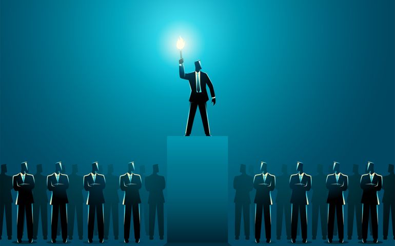 Businessman lighting up other businessmen with a torch on stage,