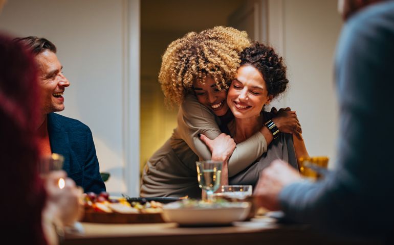 Two Friends Hugging During A Dinner Celebration