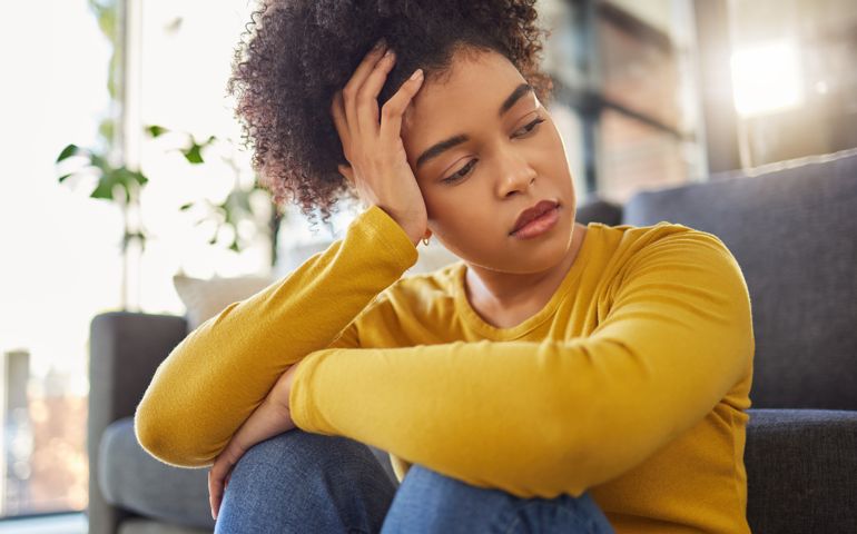 Young unhappy woman looking sad and thinking alone at home