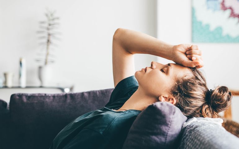 Sad and depressed woman sitting on sofa at home.