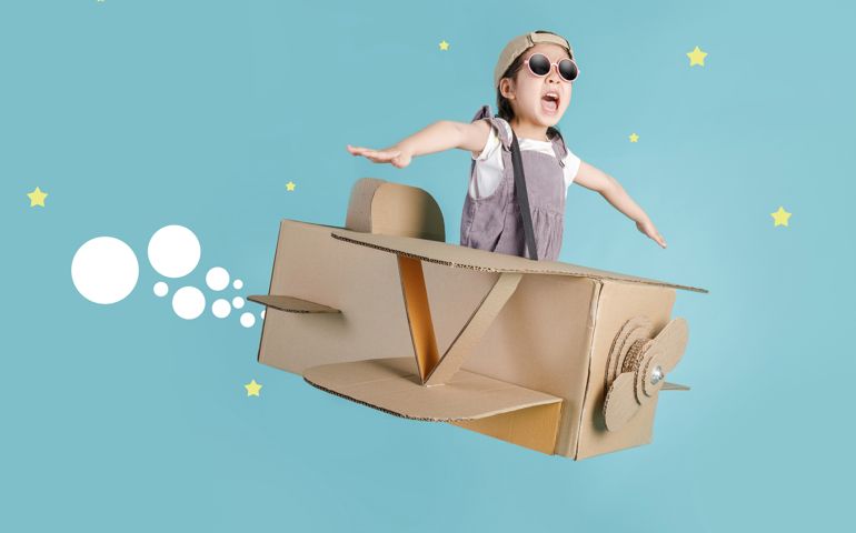 little child girl playing with cardboard toy airplane handicraft isolated on blue long banner with copy space for your text,