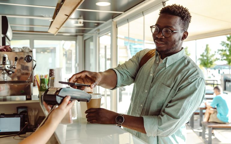 Young student paying a coffee with his phone