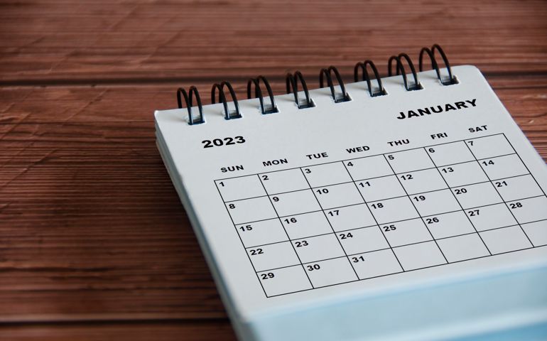 January 2023 white desk calendar on wooden table background. Calendar concept