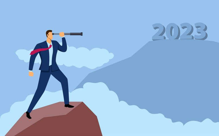 Businessman on top of a mountain looking through telescope to the year 2023
