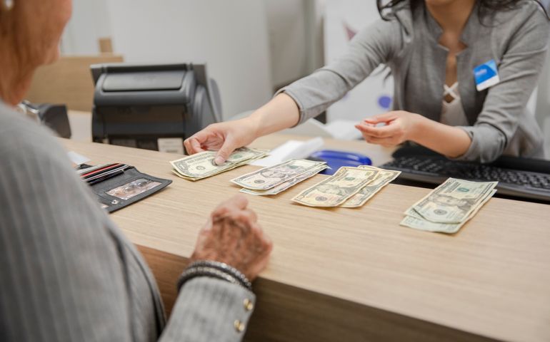 Bank teller counting cash for client at bank branch