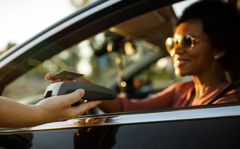 Woman paying for her order at the drive through or curbside pickup