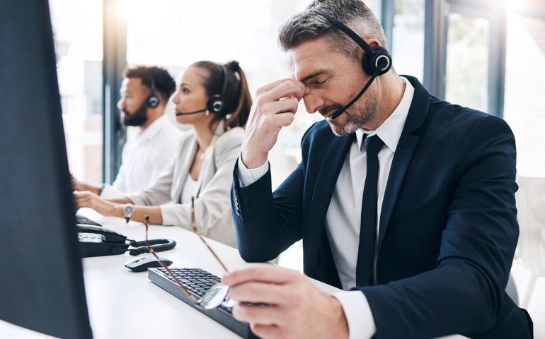 Call center, customer service and man with headache, stress and tired of working in office.