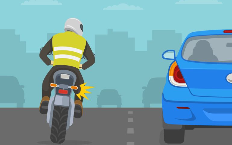 Motorcycle rider is trying to overtake the car from the left side. Back view.