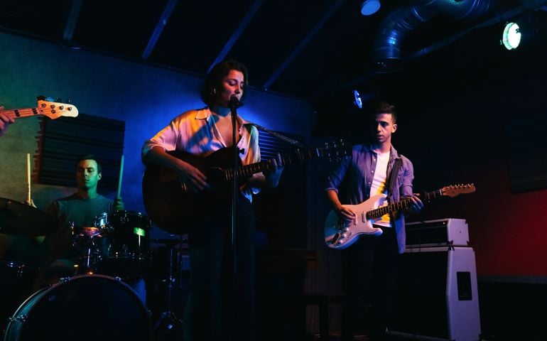 Hitting the Note: Music band singing and playing instruments on an indoor stage with colored lighting during a live concert