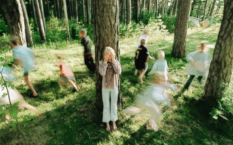 Children (6-9) playing hide and seek in forest (Blurred Motion)