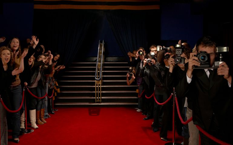Paparazzi and excited fans greeting celebrity arrivals on red carpet