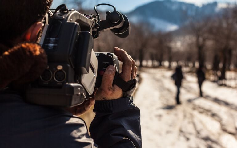 a young man using a professional camcorder outdoor